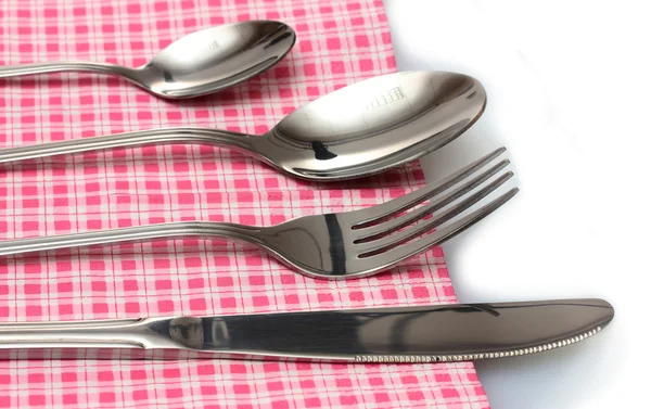 Forchetta, cucchiaio e coltello in un panno a quadri con un fiocco isolato su bianco — Foto Stock