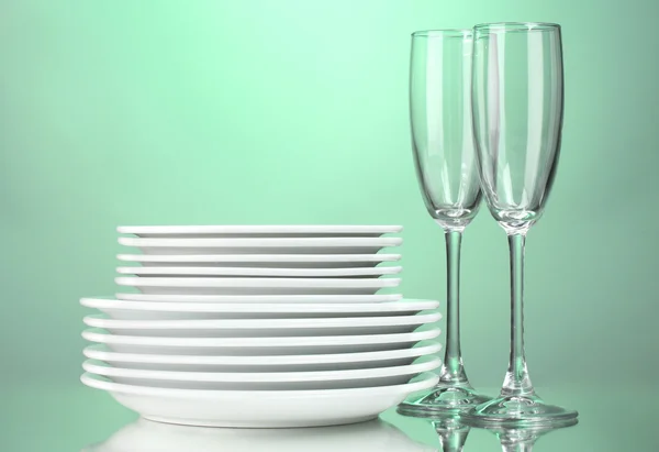 Clean plates and glasses on green background — Stock Photo, Image