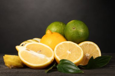 Olgun limon ve limes yapraklar gri arka plan üzerinde ahşap tablo