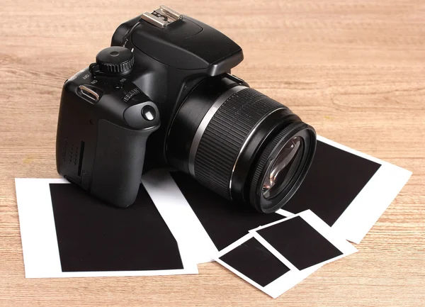 Digital photo camera with photo paper on wooden background — Stock Photo, Image