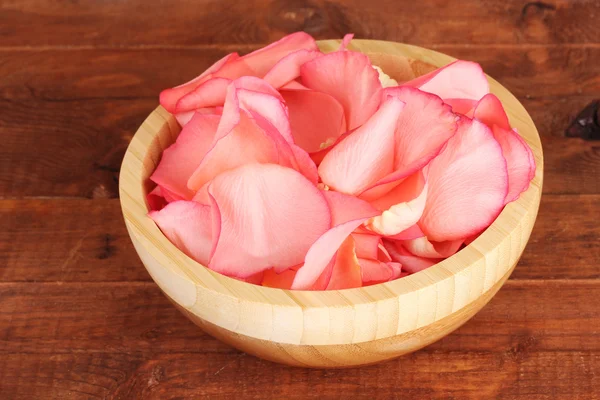 Mooie roze roze bloemblaadjes in houten kom op tafel — Stockfoto