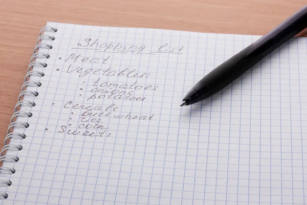 Shoping listesi ve ahşap masa üstünde kalem — Stok fotoğraf
