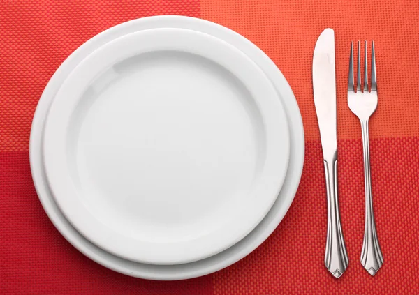 Witte lege plaat met vork en mes op een rood tafellaken — Stockfoto