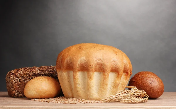 Leckeres Brot und Ohren auf Holztisch auf grauem Hintergrund — Stockfoto