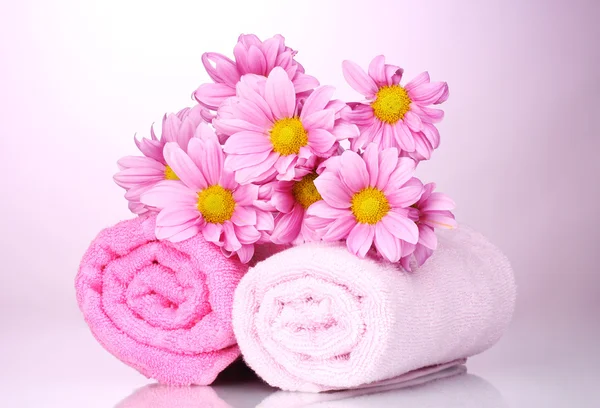 Ręczniki i piękne kwiaty na różowym tle — Zdjęcie stockowe