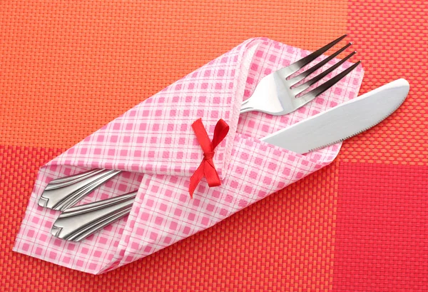Widelec i nóż w kratę tkaniny z łuku na czerwony Obrus — Zdjęcie stockowe