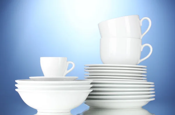 Ciotole vuote, piatti e tazze su sfondo blu — Foto Stock
