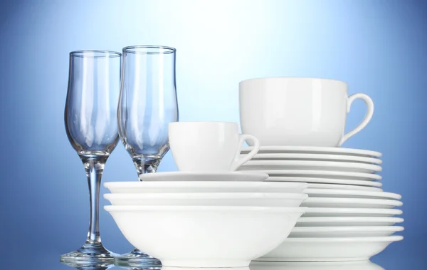 Tigelas vazias, pratos, copos e copos sobre fundo azul — Fotografia de Stock