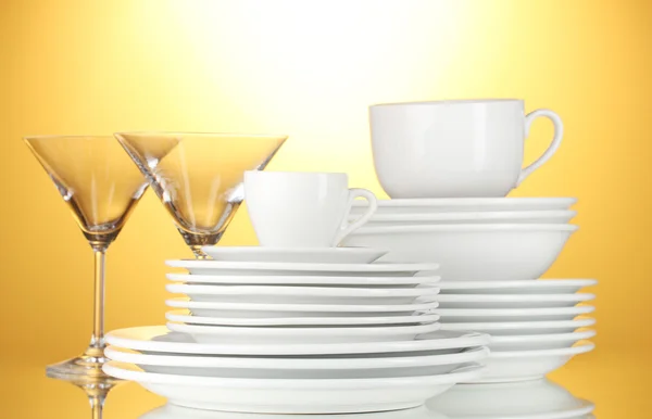 Empty bowls, plates, cups and glasses on yellow background — Stock Photo, Image