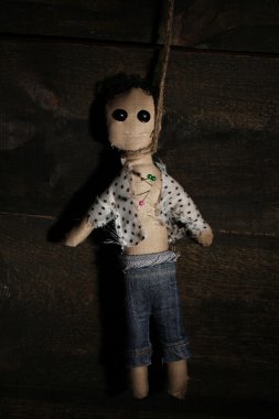 Hanged doll voodoo boy on wooden background clipart