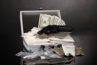 Сocaine and marijuana with gun in a suitcase on grey background clipart