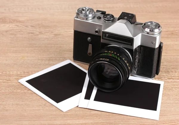 Eski fotoğraf makinesi ile fotoğraf kağıtları ahşap zemin üzerinde — Stok fotoğraf