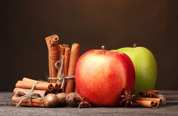 Zimtstangen, Äpfel Muskat und Anis auf Holztisch auf braunem Hintergrund — Stockfoto