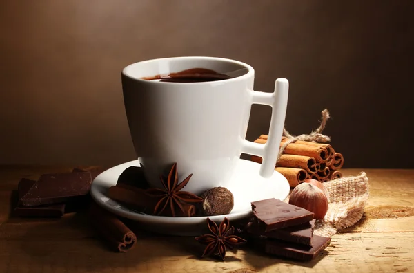 Cup of hot chocolate, cinnamon sticks, nuts and chocolate on wooden table o — Stock Photo, Image