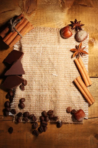 Los granos de café, las varitas de canela, las nueces y el chocolate al saquear en la mesa de madera —  Fotos de Stock