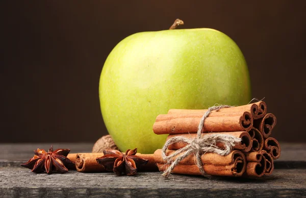 Varas de canela, maçã verde e anis na mesa de madeira no fundo marrom — Fotografia de Stock
