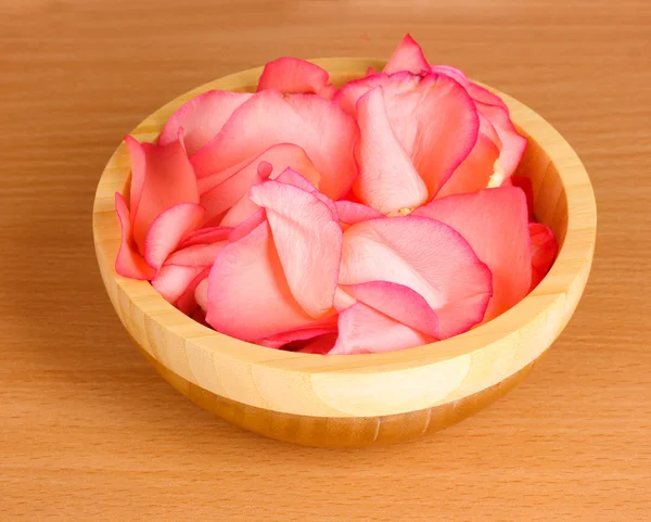 Όμορφο ροζ ροδοπέταλα σε ξύλινο μπολ στο τραπέζι — Φωτογραφία Αρχείου