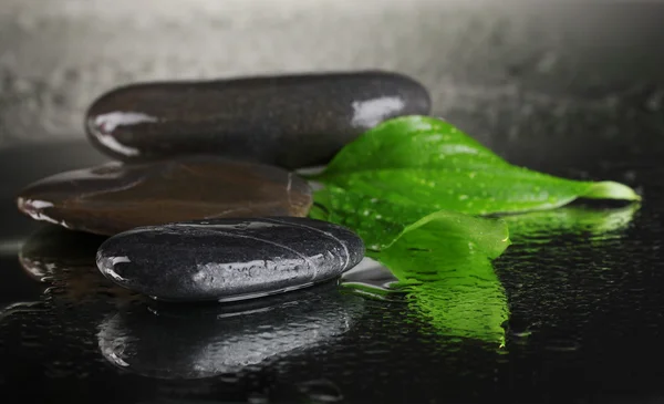 Pierres de spa avec gouttes d'eau et feuilles sur fond noir — Photo
