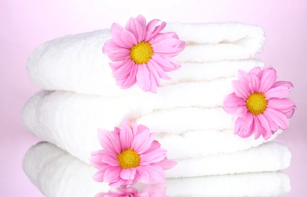 Toallas y hermosas flores sobre fondo rosa — Foto de Stock