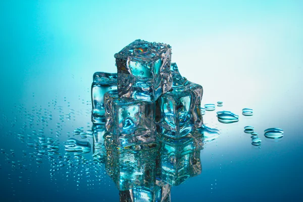 Derretimiento de cubitos de hielo sobre fondo azul — Foto de Stock