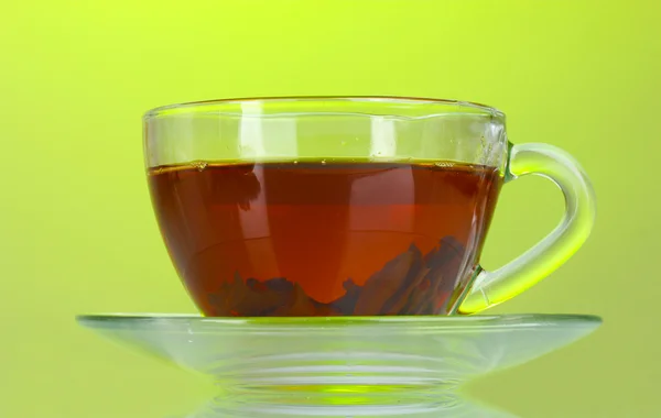 Черный чай в стеклянной чашке на зеленом фоне — стоковое фото