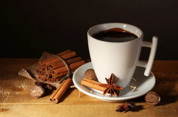 Чашка горячего шоколада, коричные палочки, орехи и шоколад на деревянном столе — стоковое фото