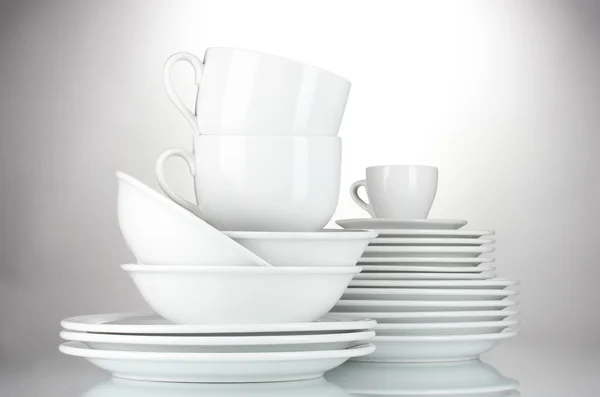 Пустые миски, тарелки и чашки на сером фоне — стоковое фото