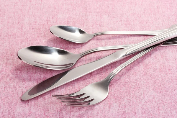 Forchetta, cucchiaio e coltello su una tovaglia rosa — Foto Stock