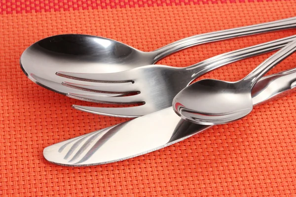 Forchetta, cucchiaio e coltello su una tovaglia rossa primo piano — Foto Stock