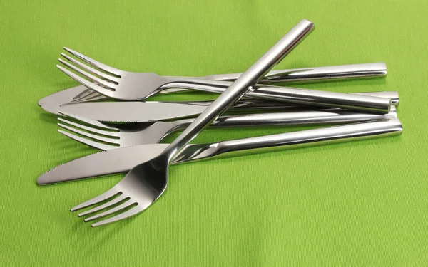 在绿色的桌布上的刀子和叉子 — 图库照片