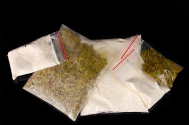 Cocaine and marihuana in packages on black background clipart