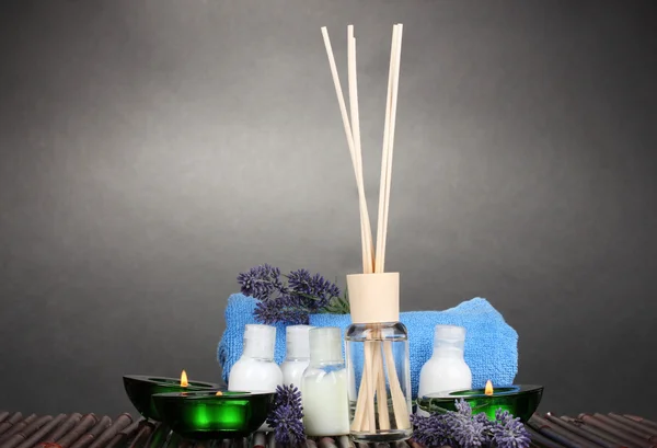 Ambientador, botellas, toallas y velas sobre alfombra de bambú sobre fondo gris —  Fotos de Stock