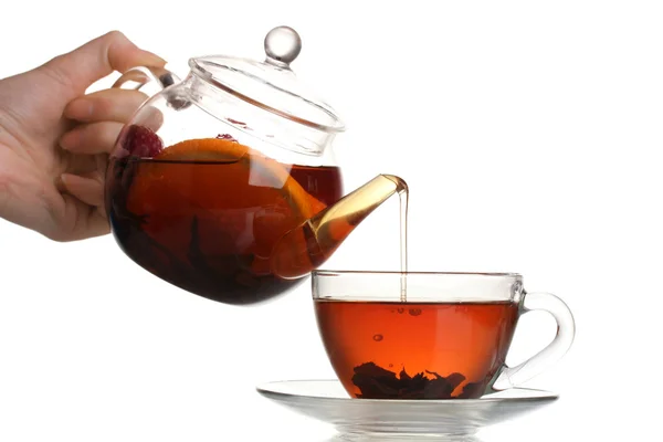 Glass teapot pouring black tea into cup isolated on white — Stock Photo, Image