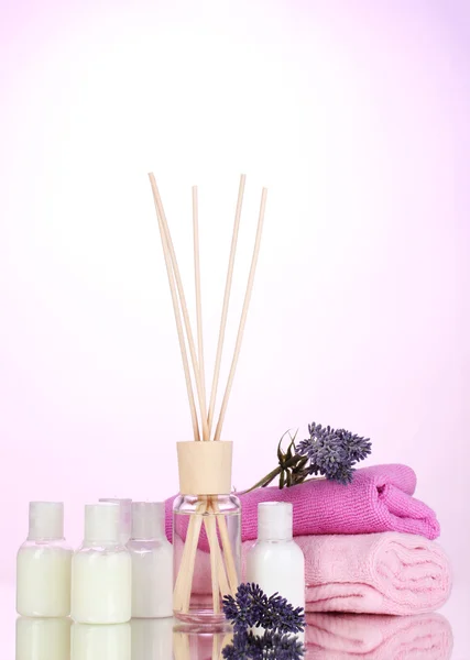 Botella de ambientador, lavanda y toallas sobre fondo rosa —  Fotos de Stock
