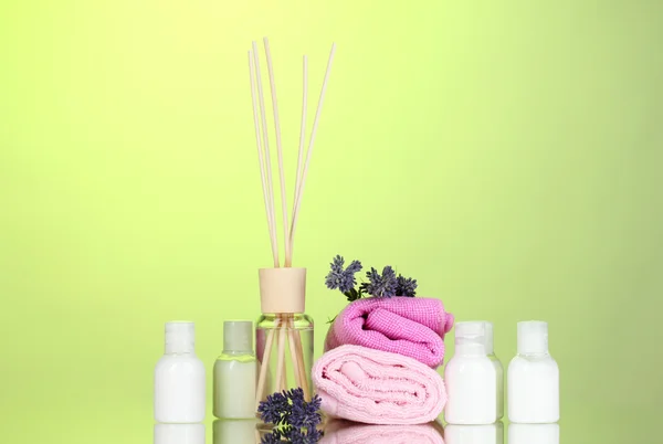Fles luchtverfrisser, lavendel en handdoeken op groene achtergrond — Stockfoto