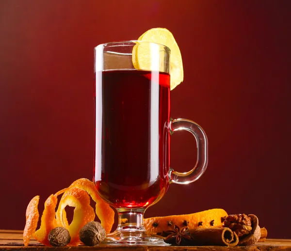 Mulled wine in the glass, spice and lemon on red background — Stock Photo, Image