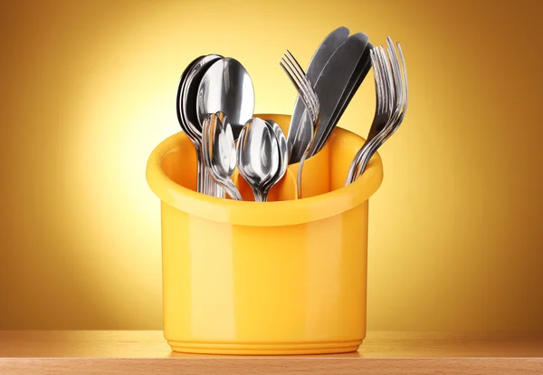 Kuchyňské příbory, nože, vidličky a lžíce v žlutý stojan na žluté backgro — Stock fotografie
