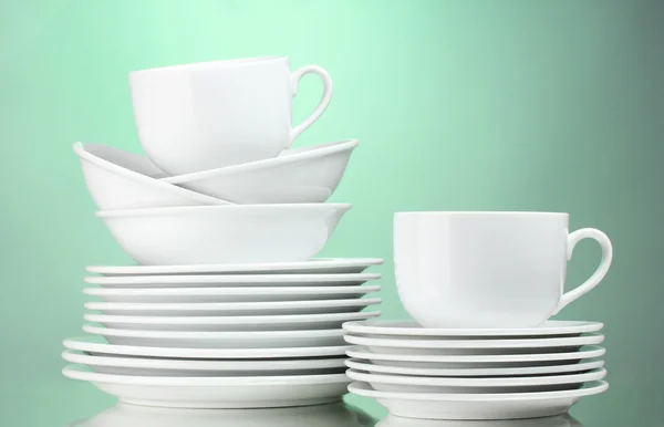 Čisté talíře, šálky na zeleném pozadí — Stock fotografie