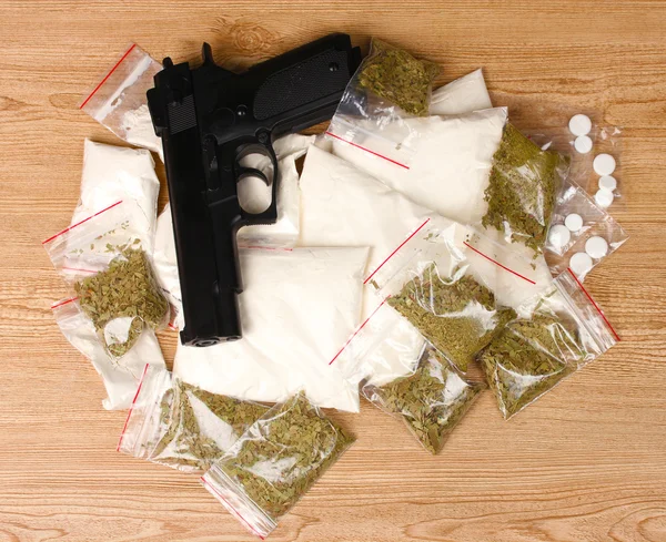 Cocaïne et marihuana en paquets et arme de poing sur fond en bois — Photo