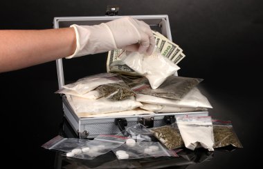 Cocaine and marijuana in a suitcase wiht hand holding a package of cocaine clipart