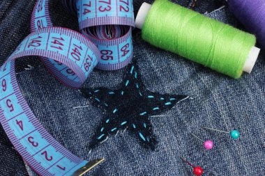 Star-shaped patch on jeans with threads and buttons closeup clipart