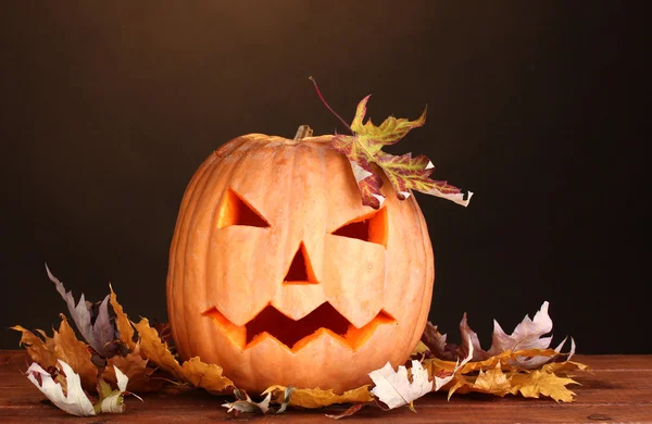 Хэллоуин Тыква и осенние листья на деревянном столе на коричневом фоне — стоковое фото