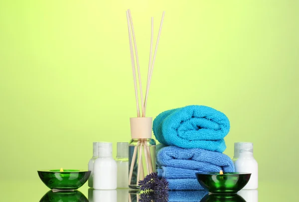 Botella de ambientador, lavanda y toallas sobre fondo verde —  Fotos de Stock