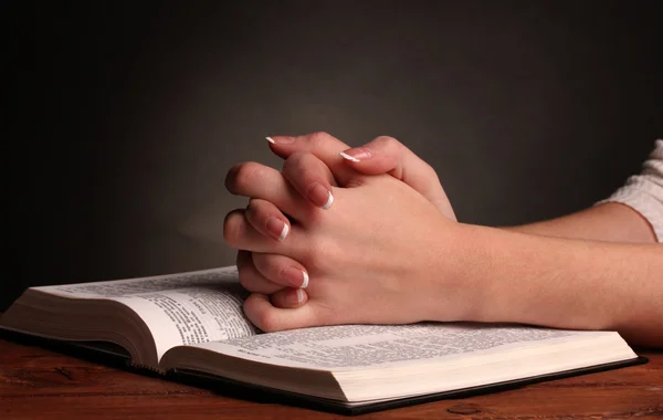 Händerna vikas i bön över öppna ryska Bibeln på svart bakgrund — Stockfoto