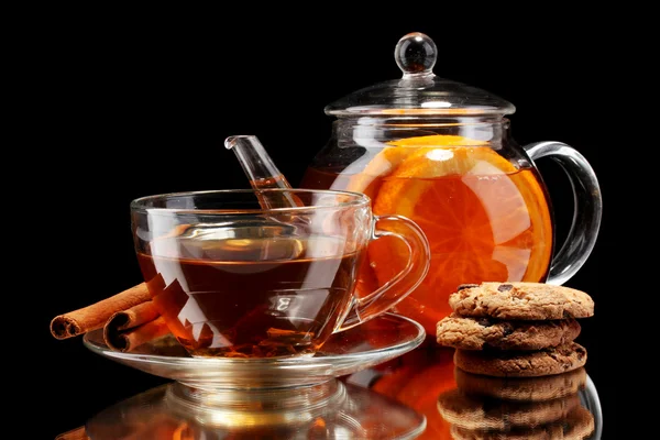 Skleněná konvice a šálek s černými Ovocný čaj a sušenky izolovaných na bílém — Stock fotografie