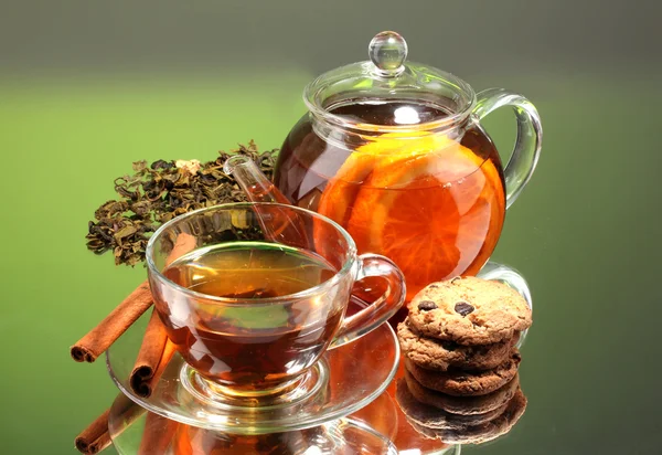Herbaty czarne owoce egzotyczne w szklany czajnik i filiżanki na zielonym tle — Zdjęcie stockowe