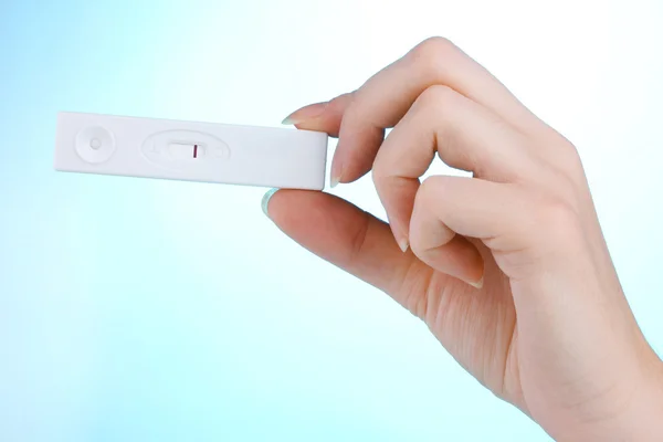 妊娠试验在蓝色背景上的手 — 图库照片