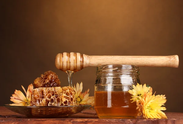 Pot met honing, honingraten en houten drizzler op tafel op gele achtergrond — Stockfoto