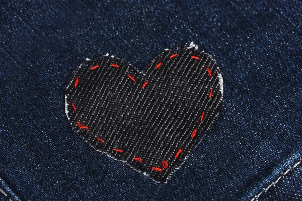 Пластырь в форме сердца на джинсах крупным планом — стоковое фото