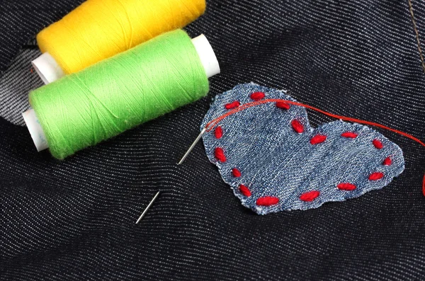 Parche en forma de corazón en jeans con hilos y aguja de primer plano — Foto de Stock